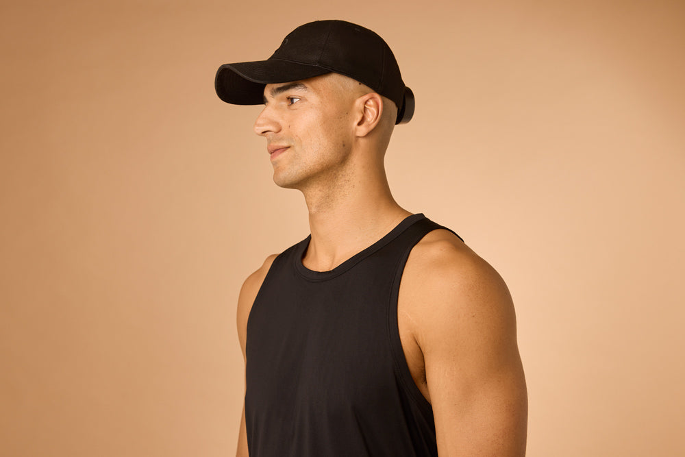 Man wearing a black cap and tank top on a beige background