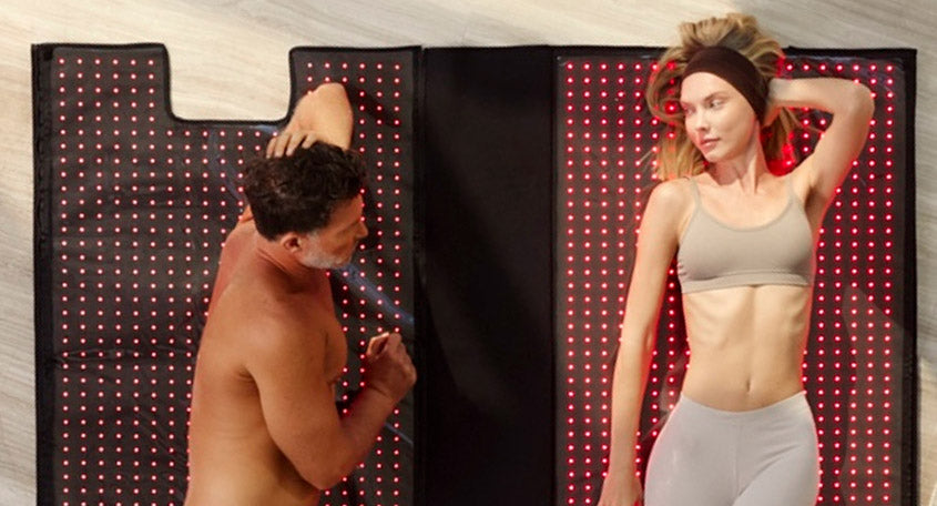 man and woman laying on red light therapy blanket